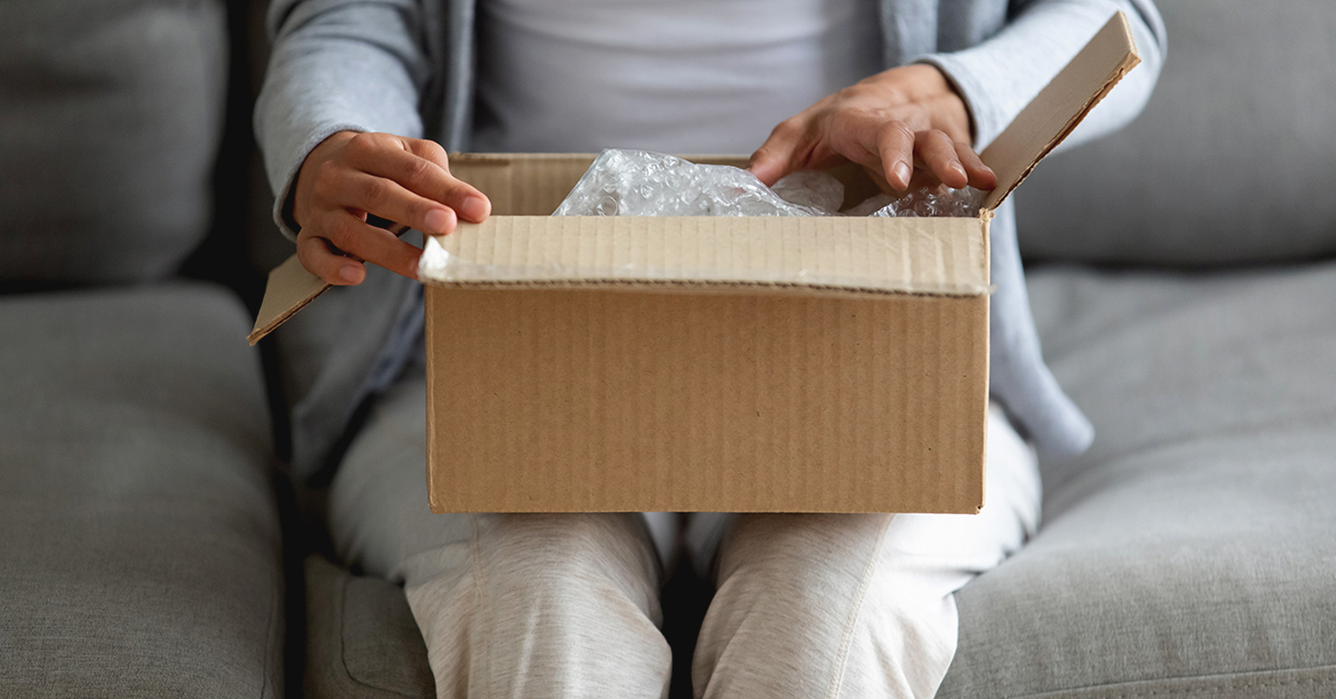 Close up view on woman lap is small carton box, female opening it and looks inside. Transport services, addressee recipient received parcel or client sending package, quick post mail delivery concept