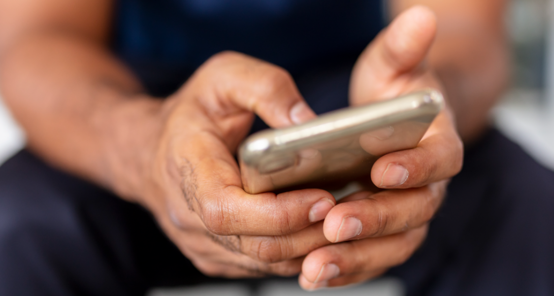 An image of a man's hands using a mobile phone.