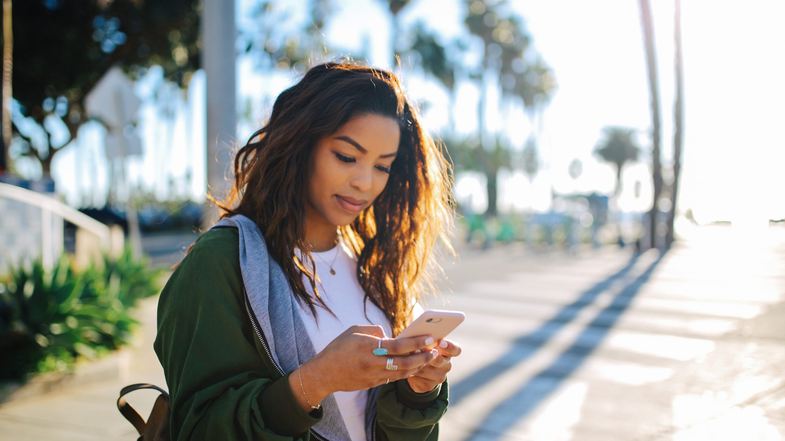 An image of a young fashionable woman reading a message on her phone.