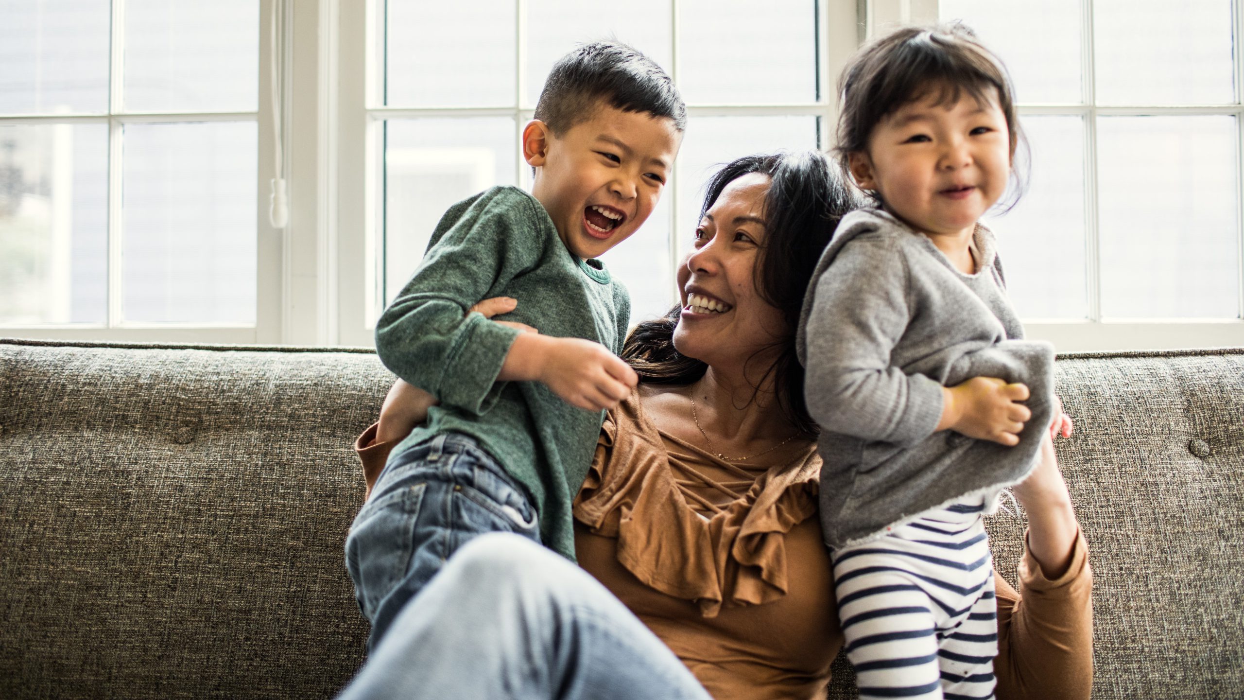 An image of a woman on a couch with two children